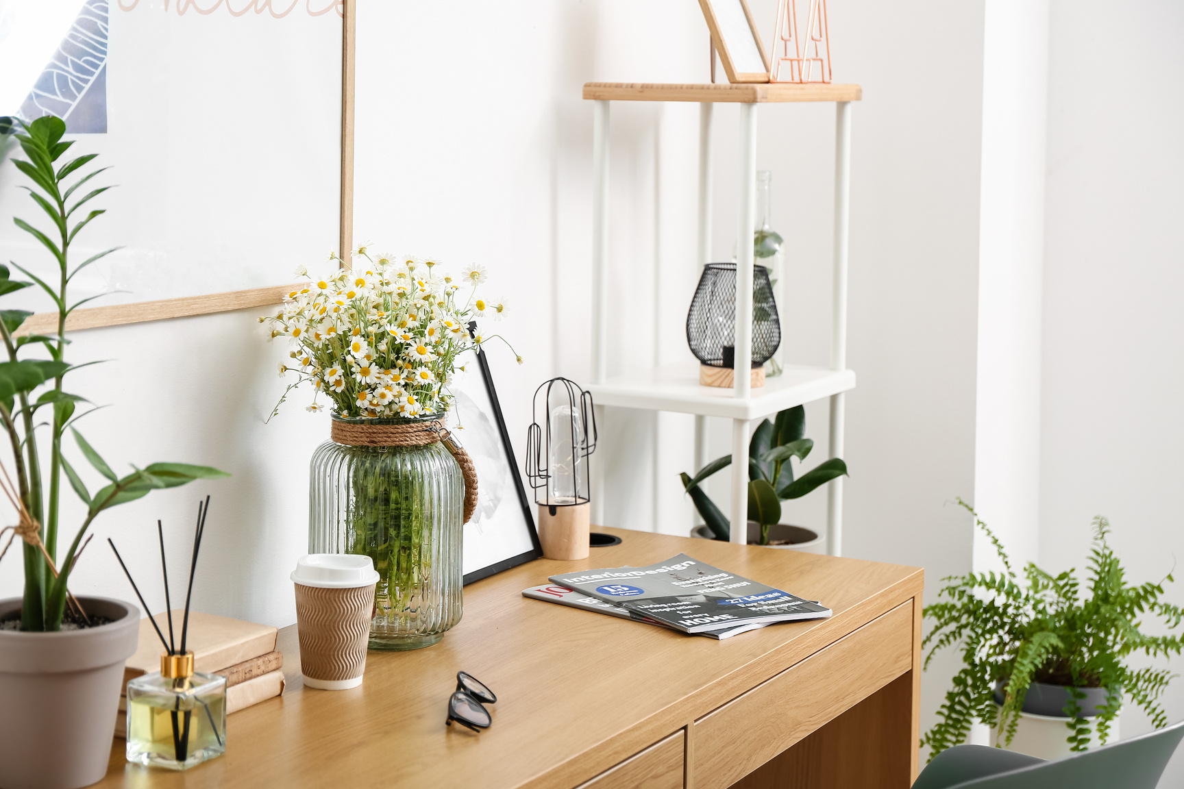 Modern Workplace and Vase with Chamomiles near Light Wall
